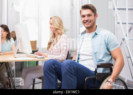 Mann im Rollstuhl lächelt Kamera vor Menschen, die Stockfoto