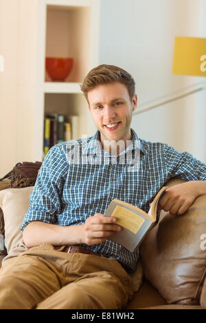 Junger Mann auf seiner Couch lesen Stockfoto