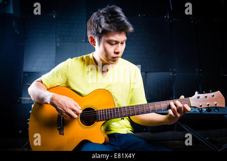 Asiatische professionelle Gitarristen spielen akustische Gitarrenmusik im Tonstudio Stockfoto