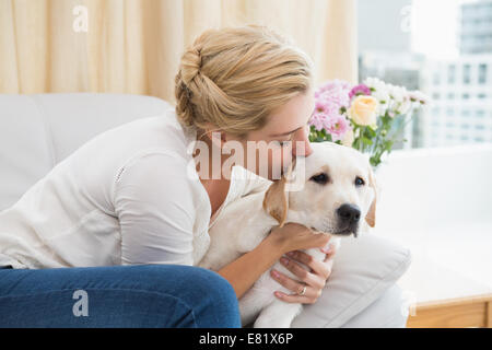 Glücklich Blondine mit Welpen auf Sofa kuscheln Stockfoto