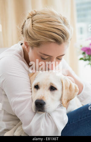 Glücklich Blondine mit Welpen auf Sofa kuscheln Stockfoto