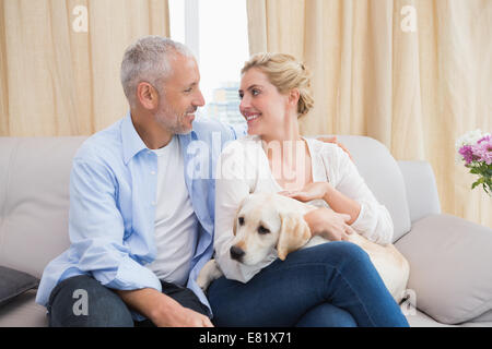 Brautpaar mit Welpen auf Sofa kuscheln Stockfoto