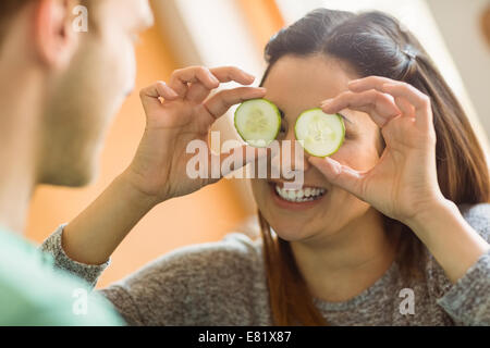 Niedliche Brünette mit Gurkenscheiben über Augen Stockfoto