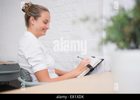 Geschäftsfrau in Tagebuch im Büro zu schreiben Stockfoto