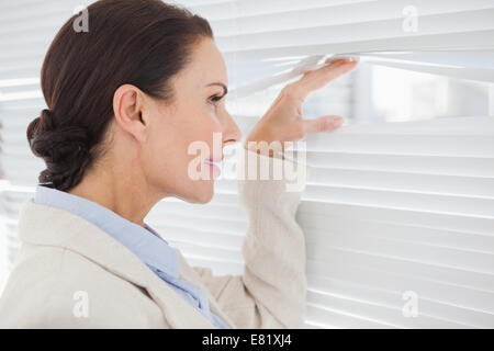 Geschäftsfrau sucht durch einige Jalousien Stockfoto