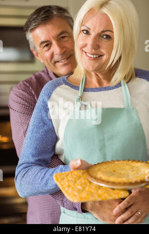 Reife Blondine hält frische Torte mit Mann umarmt Ihr Stockfoto