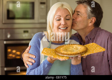 Reife Blondine hält frische Torte mit Mann küssen Stockfoto