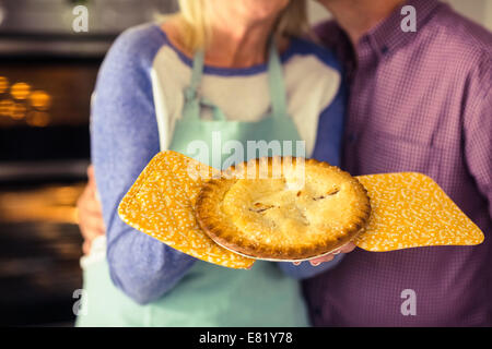 Reife Blondine hält frische Torte mit Mann küssen Stockfoto