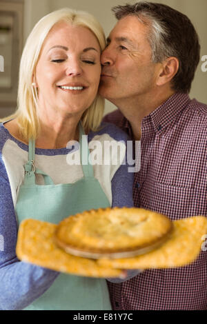 Reife Blondine hält frische Torte mit Mann küssen Stockfoto