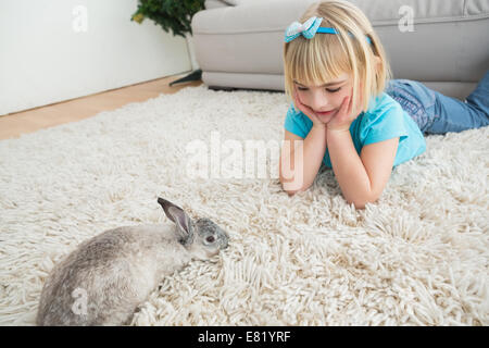 Kleines Mädchen auf Teppich liegend mit Kaninchen Stockfoto