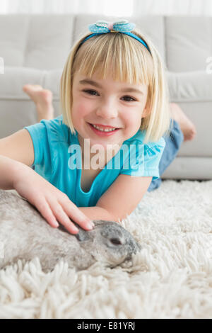 Kleines Mädchen liegend auf Teppich die Kaninchen streicheln Stockfoto