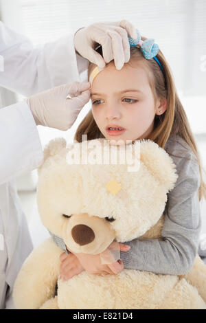 Mädchen bekommen ein Pflaster auf der Stirn Stockfoto