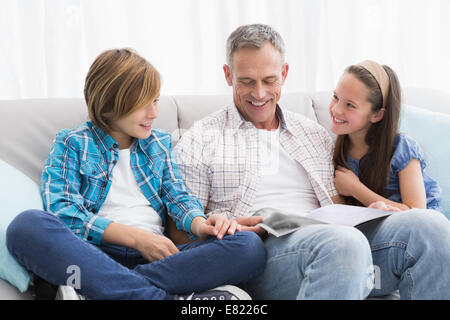 Glückliche Familie auf der Couch lesen Bilderbuch Stockfoto