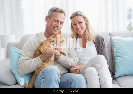 Lächelnde paar streicheln ihre Gringer Katze auf der couch Stockfoto