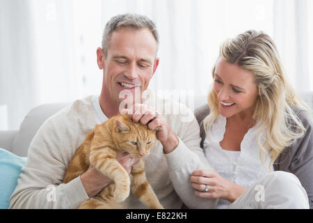 Lächelnde paar streicheln ihre Gringer Katze auf der couch Stockfoto