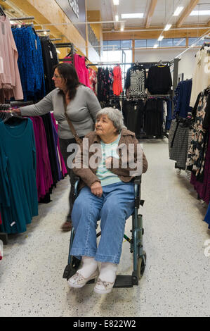 Ältere Frau im Rollstuhl und ihre Pfleger oder Assistent Einkauf für die Kleidung. Stockfoto