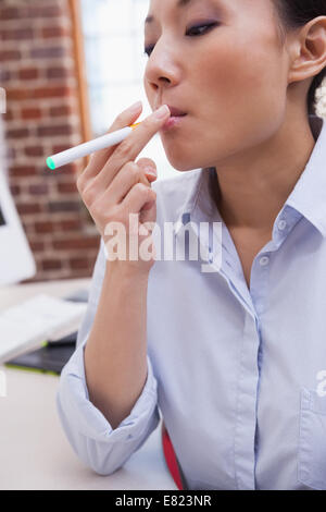 Lässige Geschäftsfrau, die eine elektronische Zigarette rauchen Stockfoto