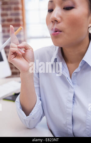 Lässige Geschäftsfrau, die eine elektronische Zigarette rauchen Stockfoto