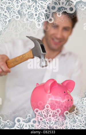 Lässige Geschäftsmann brechen Sparschwein mit hammer Stockfoto