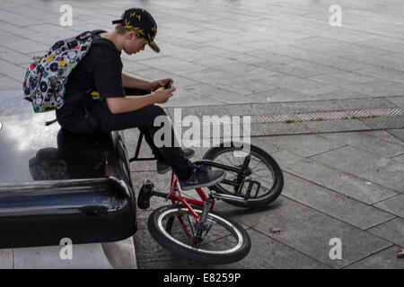 Ein junger Teenager befasst sich mit einem Smartphone sitzend mit seinem Motorrad In Sheffield UK Stockfoto