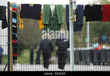 Burbach, Deutschland. 29. Sep, 2014. Sicherheitspersonal (Hintergrund) ist zu Fuß auf der Website von einem Flüchtlingsheim in der ehemaligen Siegerland-Kaserne während Wäsche von einem Zaun in Burbach, Deutschland, 29. September 2014 hängt abgebildet., privates Sicherheitspersonal hat angeblich verletzt und angegriffene Menschen Asyl in einem Flüchtlingslager in Burbach zu Hause. Die ehemalige Siegerland Baracken dient als ein Notunterkünfte für Flüchtlinge und Asylsuchenden Menschen. Bildnachweis: Dpa picture Alliance/Alamy Live News Stockfoto