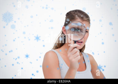 Junge Frau, die durch ein Vergrößerungsglas Stockfoto