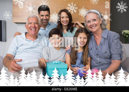 Zusammengesetztes Bild Großfamilie auf Sofa mit Geschenk-Boxen im Wohnzimmer Stockfoto