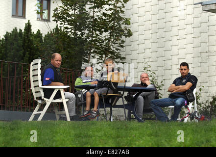 Burbach, Deutschland. 29. Sep, 2014. Serbische Flüchtlinge sitzen vor einem Gebäude in einem Flüchtlingsheim in der ehemaligen Siegerland-in Burbach, Deutschland, 29. September 2014 Kaserne. Private Security-Personal hat angeblich verletzt und angegriffen Menschen Asyl in einem Flüchtlingslager in Burbach. Die ehemalige Siegerland Baracken dient als ein Notunterkünfte für Flüchtlinge und Asylsuchenden Menschen. Foto: INA FASSBENDER/DPA/Alamy Live-Nachrichten Stockfoto