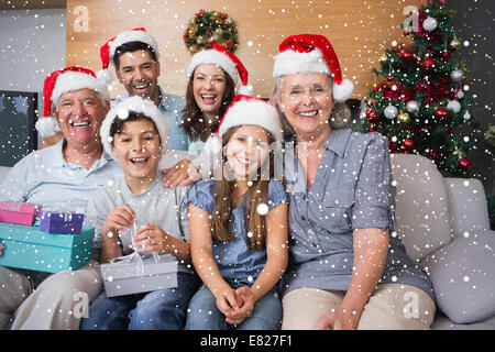 Großfamilie in Weihnachtsmützen mit Geschenk-Boxen im Wohnzimmer Stockfoto