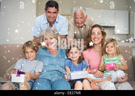 Zusammengesetztes Bild der Geschwister halten Geschenke mit Familie im Wohnzimmer Stockfoto