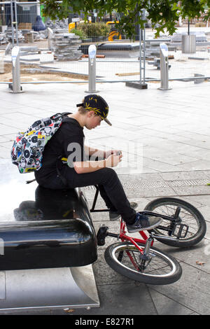 Ein junger Teenager befasst sich mit einem Smartphone sitzend mit seinem Motorrad In Sheffield UK Stockfoto