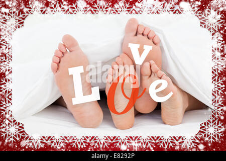 Zusammengesetztes Bild paar Füße unter der Bettdecke mit Liebe text Stockfoto