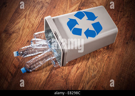 Gespiegelte Papierkorb voll von Kunststoff-Flaschen auf eine Holzoberfläche Stockfoto