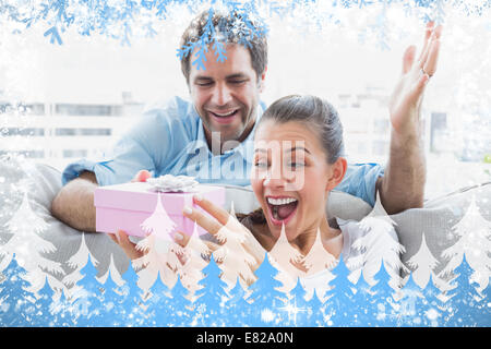 Mann überraschend seine hübsche Freundin mit einem rosa Geschenk auf dem sofa Stockfoto
