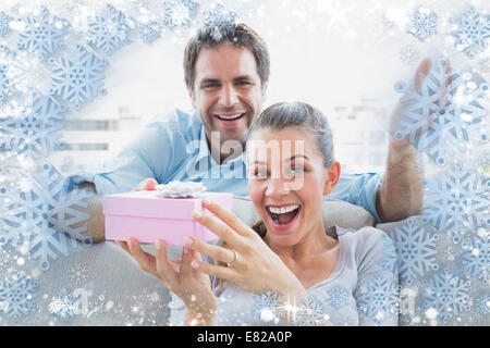 Mann überraschend seine Freude Freundin mit einem rosa Geschenk auf dem sofa Stockfoto