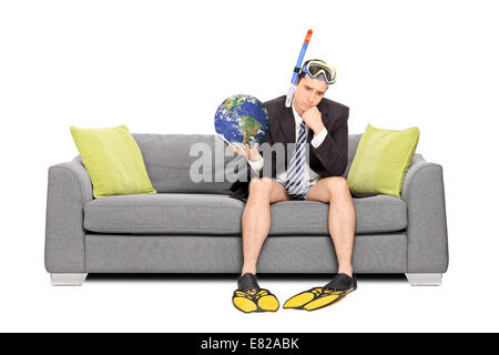 Traurig Geschäftsmann die Erde halten und sitzen auf dem Sofa isoliert auf weißem Hintergrund. Earth-Bild im Public Domain und eingerichtete b Stockfoto