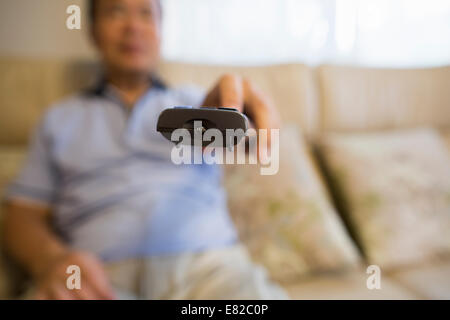 Mann sitzt auf dem Sofa mit Fernbedienung. Stockfoto