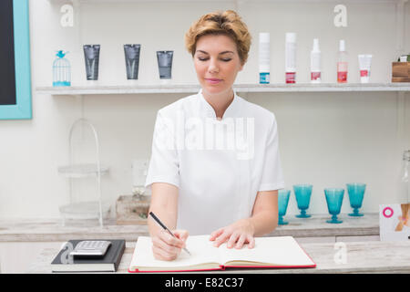 Hübsche Kosmetikerin im Terminkalender schreiben Stockfoto
