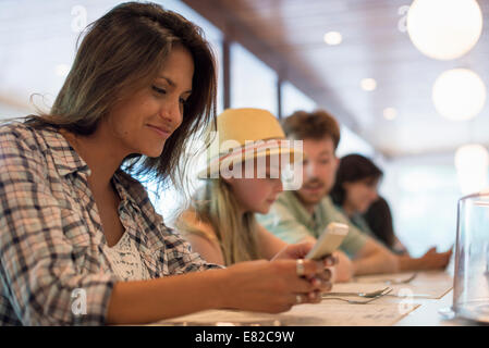 Eine Frau in einem Diner, Blick auf ihr Handy. Stockfoto