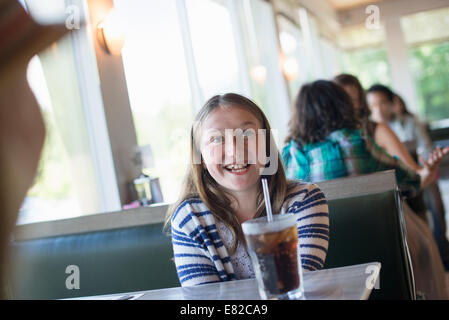 Ein Kind sitzt in einem Diner mit einem großen kalten Getränk in ein Glas mit einem Strohhalm. Stockfoto