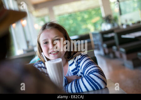 Ein junges Mädchen mit einer großen Milchshake an einem Diner Tisch. Stockfoto