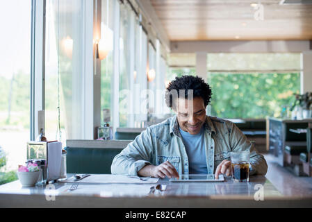 Ein Mann sitzt in einem Diner mit einem digitalen Tablet. Stockfoto