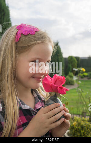 Junges Mädchen riechen eine rote Rose. Stockfoto