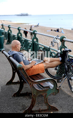 Hove Brighton UK - Mann sitzt am Meer Bank in Hove arbeiten auf einem Laptop-Computer Stockfoto