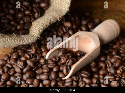 Kaffee Bohnen verschütten aus einer Jute-Tasche auf einem Vintage Karte Oberfläche mit einer Schaufel Stockfoto