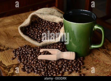 Eine grüne Kaffeebecher mit Bohnen auf eine Tischplatte Vintage Karte Stockfoto
