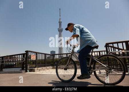 Ein älterer Japaner fährt mit dem Fahrrad in der Nähe des Tokyo Skytree in Asakusa, Tokio, Japan. Stockfoto