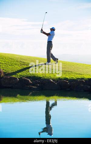 Silhouette der Mann spielt Golf auf wunderschönen Platz, Spiegelung im Wasser Stockfoto