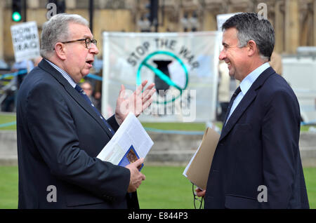 Keith Simpson MP Gespräch mit Bernard Jenkin MP (beide konservativ) am College Green Westminster - Stop The War Coalition banner Stockfoto