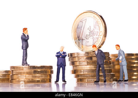 Modellfiguren von Geschäftsleuten mit €-Münzen. Stockfoto